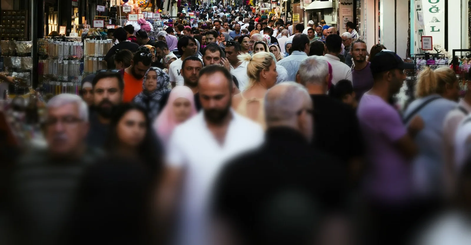 A crowded market street, shoppers filling the lane between stalls.